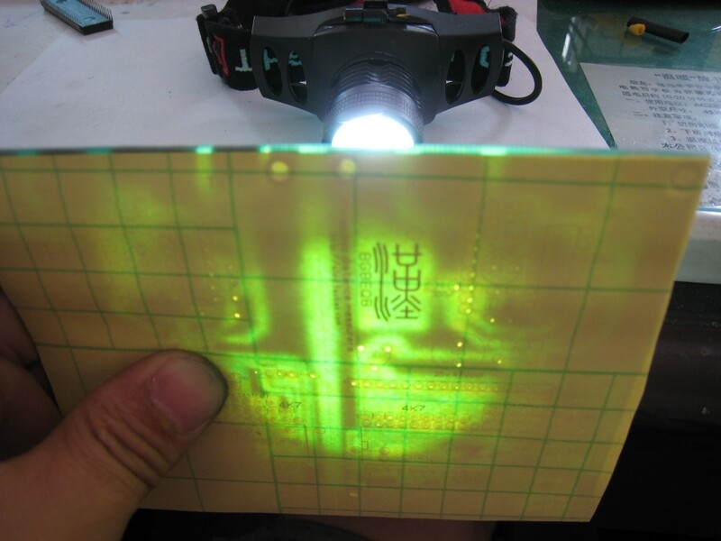 把顶层剪好的纸对好PCB板。用强光LED电筒对照，对好丝网。
